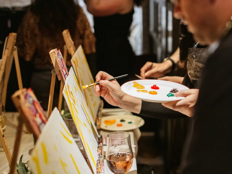 People painting with brushes and canvas in a paint and sip class